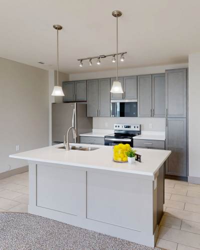 Modern kitchen with granite countertops, stainless steel appliances, and pendant lights over an island at Latitude at Deerfield Crossing in Mason, Ohio