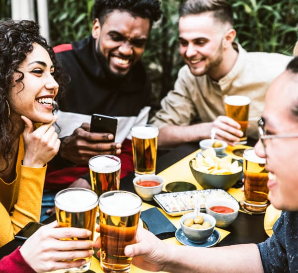 A smiling group of friends lifting their drinks in a restaurant near Astoria in Mobile, Alabama