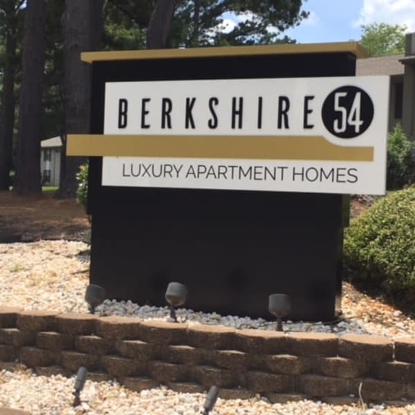 Exterior leasing center sign surrounded by a cool landscape of rocks and flowers at Berkshire 54 in Carrboro, North Carolina