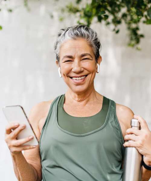 Resident smiling while holding her phone at Athens Vista Senior Apartments in Los Angeles, California