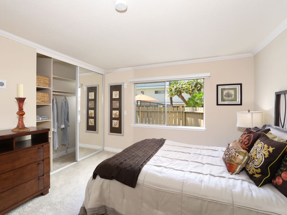 Well-decorated master bedroom with plush carpeting and mirrored closet doors in a model home at Sofi Redwood Park in Redwood City, California