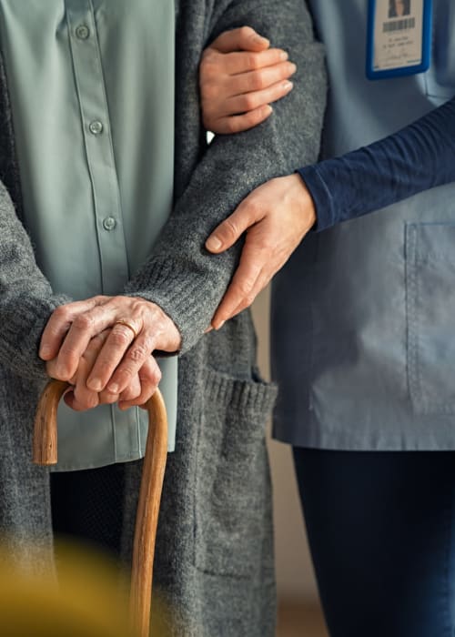 Caregiver assisted resident with a cane at The Pillars of Mankato in Mankato, Minnesota