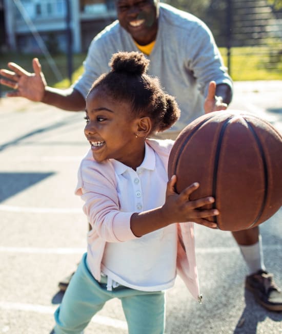 Child and parent playing basketball at a public park near Big Sky Flats in Washington, District of Columbia