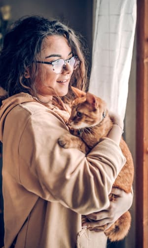 Resident cuddling her cat in their pet-friendly home at River Ranch in Sherman, Texas