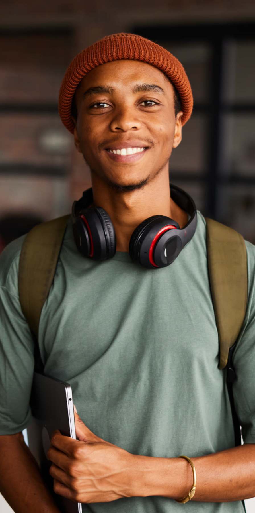 Student posing for a photo with laptop in hand at Midtown 905 in Denton, Texas