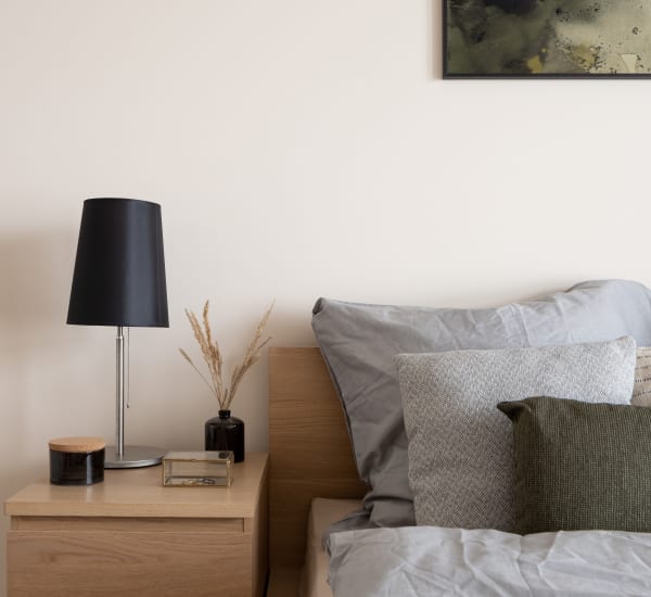 A furnished bedroom with a well-made bed, side table and lamp at Mode at Hyattsville in Hyattsville, Maryland Mode at Hyattsville in Hyattsville, Maryland