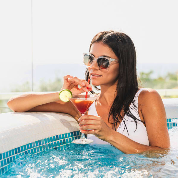 Resident relaxing with a cocktail in the pool at Olympus at Ten Mile in Meridian, Idaho