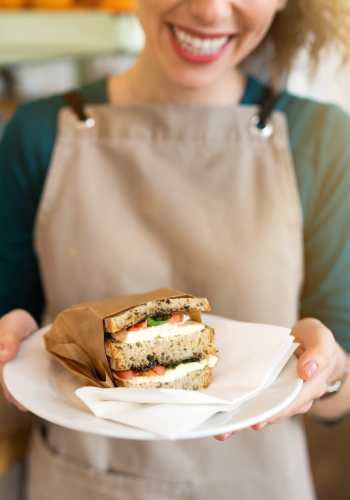 A woman holding a sandwich in a plate at Heron Creek Apartments in Moses Lake, Washington