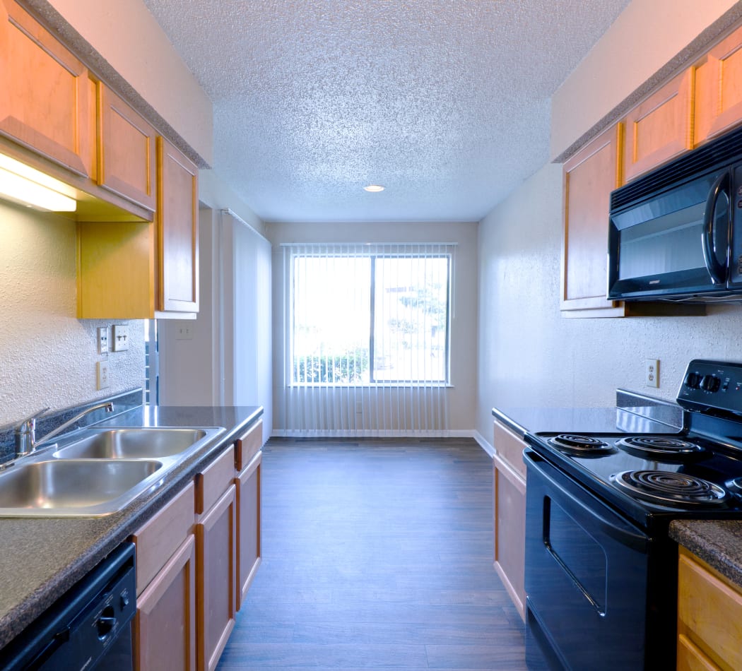 Black appliances and hardwood floors in model home's kitchen at The Belmont in Grand Prairie, Texas