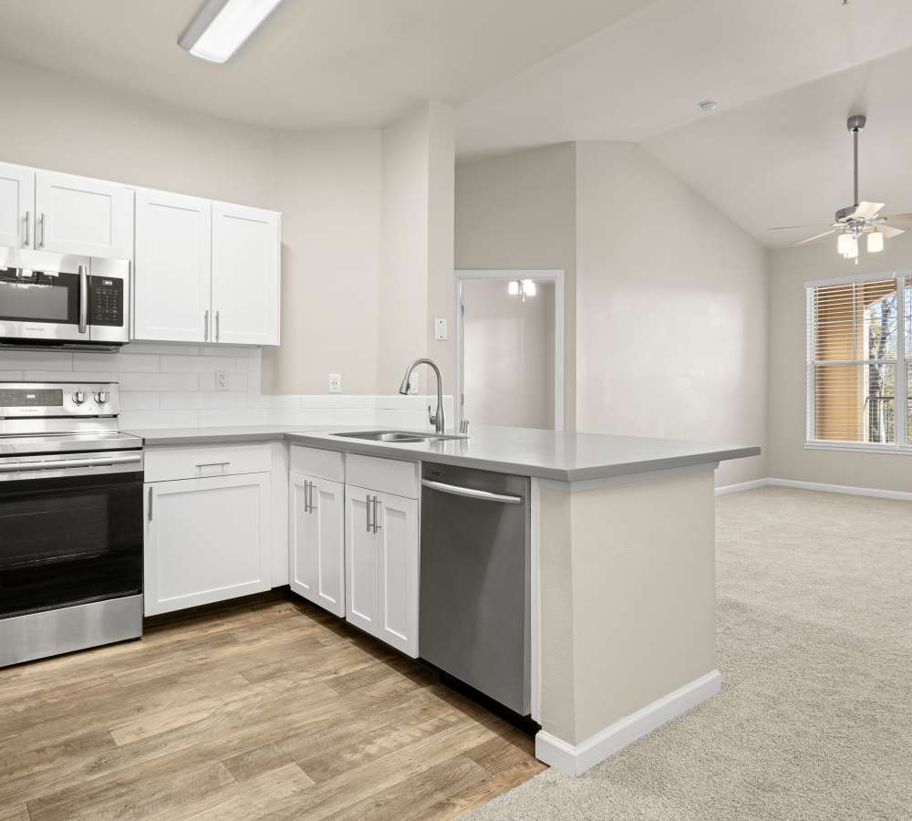 Luxury kitchen with white cabinets, grey quartz counters, and stainless steel appliances at Veridian at South Meadows in Reno, Nevada