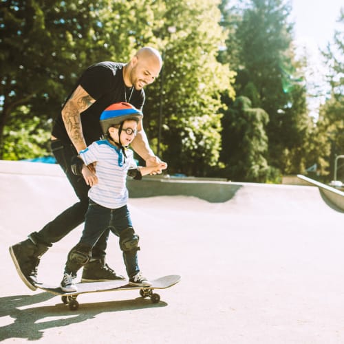 A resident helping his son ride a skateboard at a park near Adobe Flats IV in Twentynine Palms, California