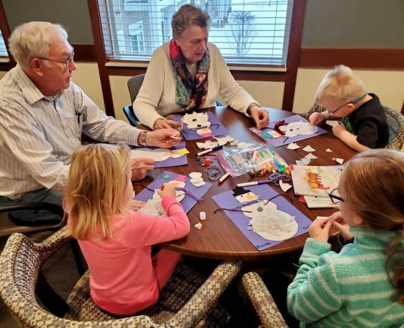 Residents and children doing arts and crafts together at Arbor Glen Senior Living in Lake Elmo, Minnesota