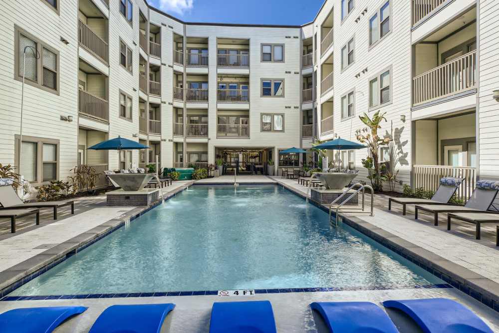 Exterior and pool with seating and umbrellas at Soba Apartments in Jacksonville, Florida