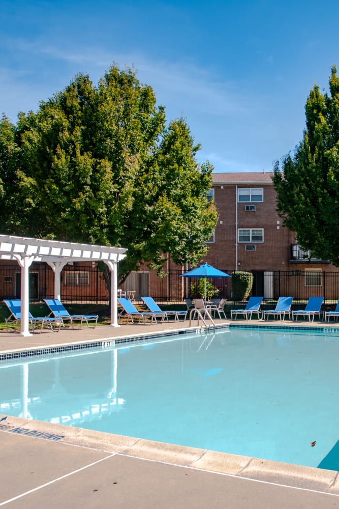 Swimming pool surrounded by lounge chairs at Hill Brook Place Apartments in Bensalem, Pennsylvania