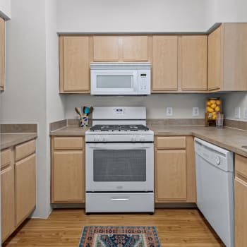 Energy efficient white appliances and with blonde wood cabinets in an apartment kitchen at Cypress Creek at Lakeline in Cedar Park, Texas
