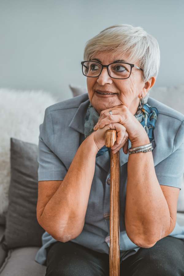 Resident smiling while holding a cane at Merrill Gardens at Cedar Mill in Portland, Oregon