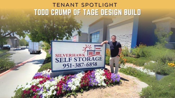 Tenant Todd Crump, owner of TAGE Design Build, stands beside the Silverhawk Self Storage sign surrounded by vibrant flower beds, highlighting his feature in the facility’s tenant spotlight blog post.