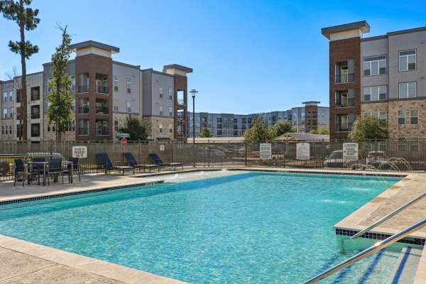 Resort-style pool at a 55+ active adult community with apartment buildings in the background