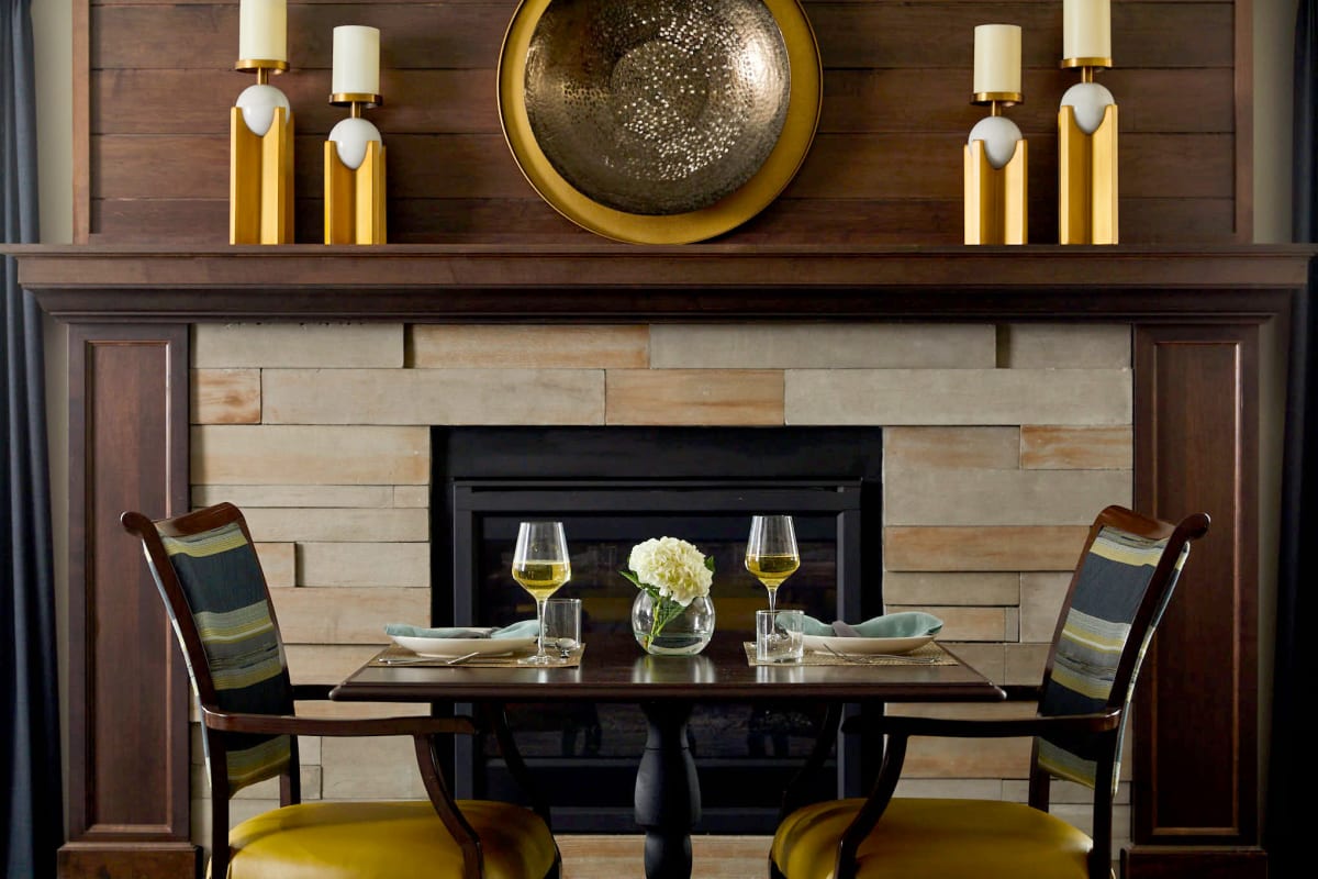 Beautifully set table for two in front of a fireplace at Amira Choice Plymouth in Plymouth, Minnesota