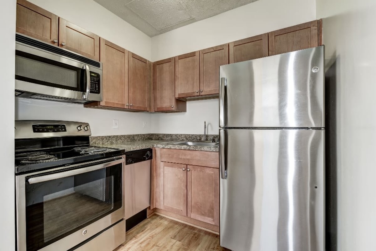 Stainless steel appliances and gorgeous wooden cabinets in the kitchen at The Envoy Apartments in Washington, District of Columbia