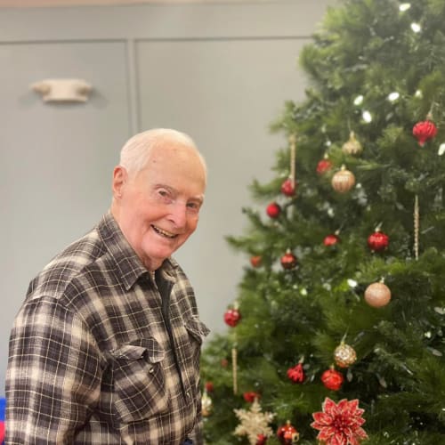 Smiling resident by a tree at Oxford Glen Memory Care at Owasso in Owasso, Oklahoma