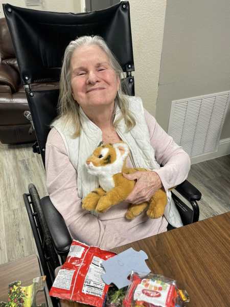 Resident smiling with stuffed animal during puzzle activity at The Landing at Watermere Frisco in Frisco, TX, enjoying memory care engagement.