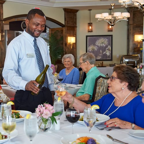 A staff member pours a glass of wine for a resident in the dining room at The Crossings at Eastchase in Montgomery, Alabama