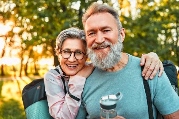Smiling 55+ couple walking together outdoors on a scenic path surrounded by trees in Conroe Texas