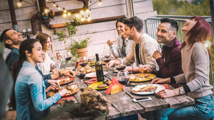 Young friends dining together outside and having red wine