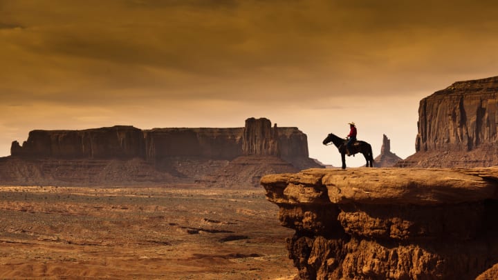 A man on a horseback overlooking a bluff 