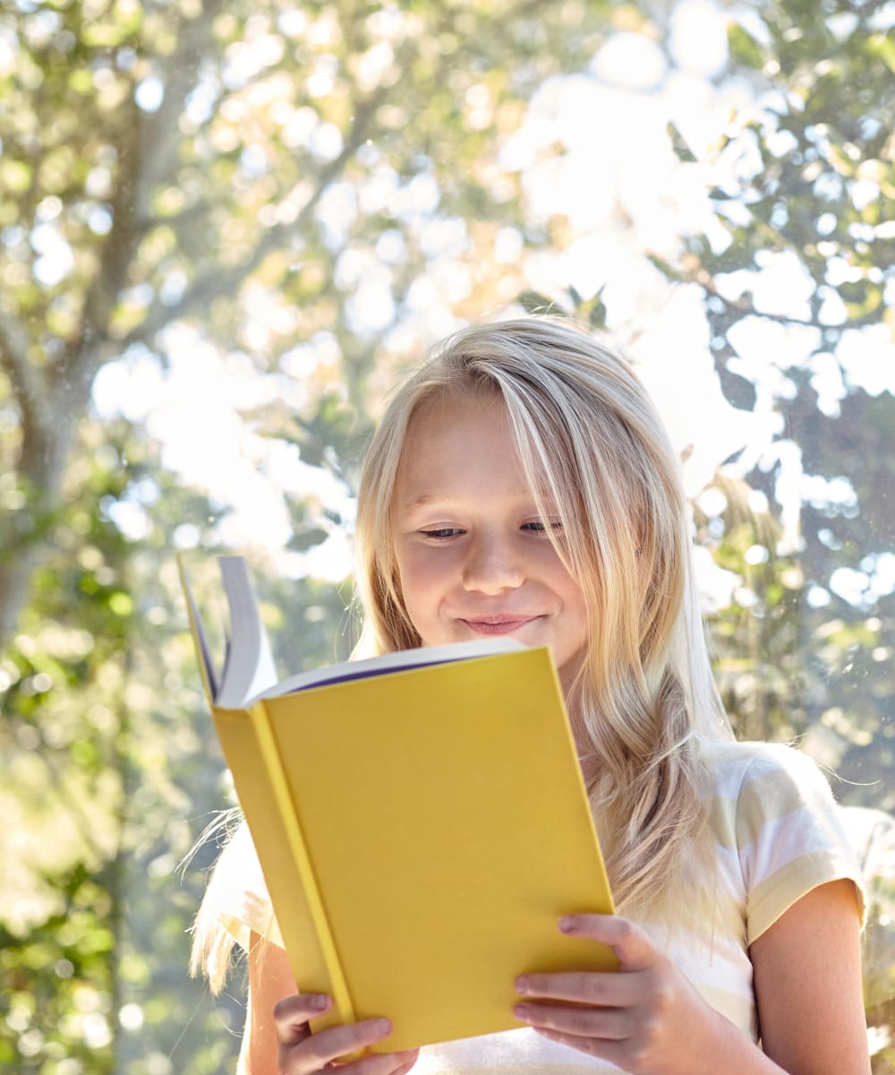 Child reading a book on a very nice day at the park near Sofi Belmar in Lakewood, Colorado