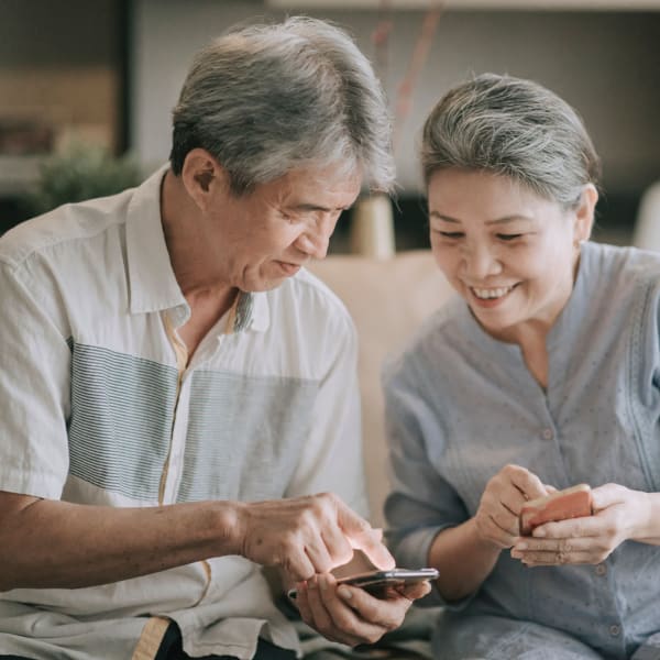 A couple looking at their phones at Pacifica Senior Living Encinitas in Encinitas, California