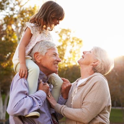 Grandparents playing with their granddaughter outdoors at Westminster Memory Care in Lexington, South Carolina