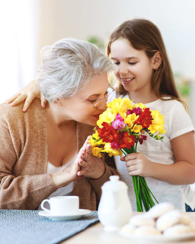 resident smelling flowers picked by her grandchild at Garden Place Senior Living