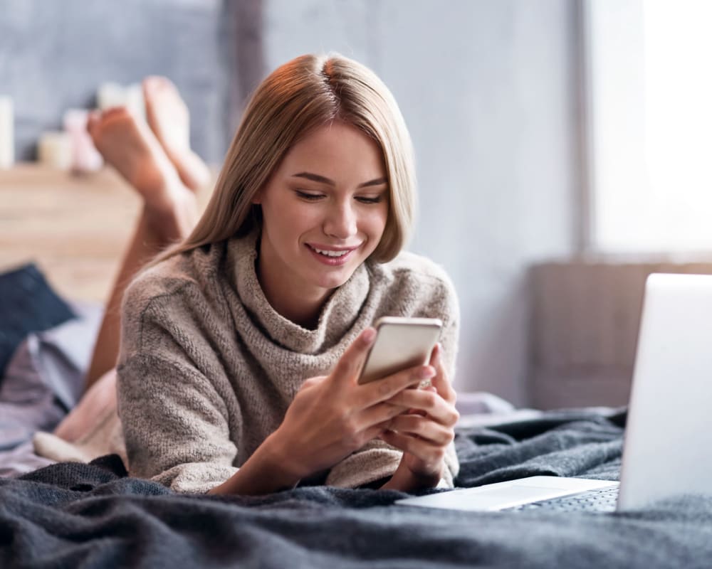 Resident laying in bed and texting at Rose Hill Estates in Norwich, Connecticut