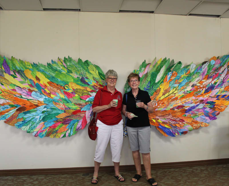 Two residents pose in front of art at Ebenezer Ridges Campus in Burnsville, Minnesota.