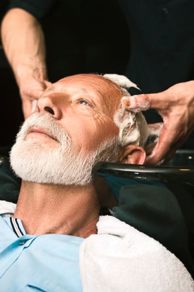 Resident getting a scalp massage in the salon at Quail Park Memory Care Residences of Visalia in Visalia, California