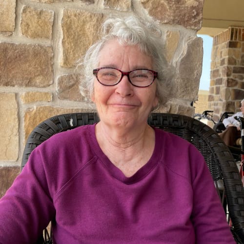 Resident sitting on a plush chair at Saddlebrook Oxford Memory Care in Frisco, Texas