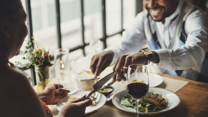 A man and woman share a fine meal with wine and salmon