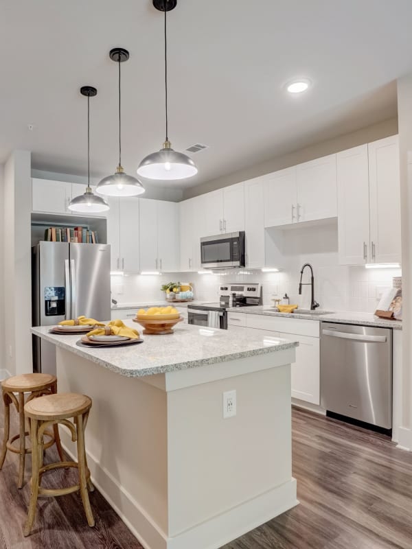 Kitchen with island, white cabinets, designer lighting and stainless steel appliances at The Mallory in Raleigh, North Carolina