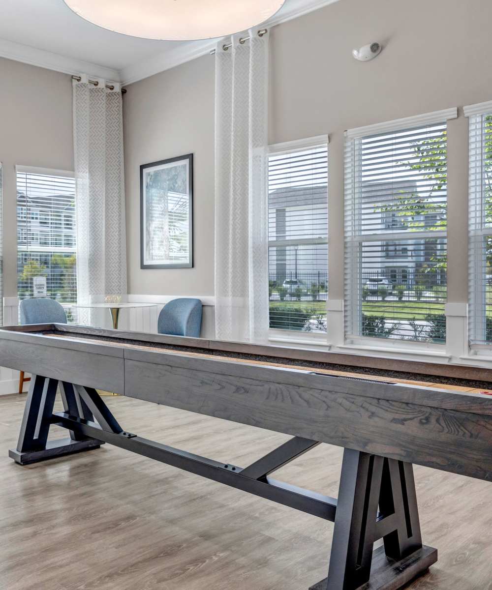 Bright game room with shuffleboard and large windows at The Carlton At Lake Dexter in Winter Haven, Florida