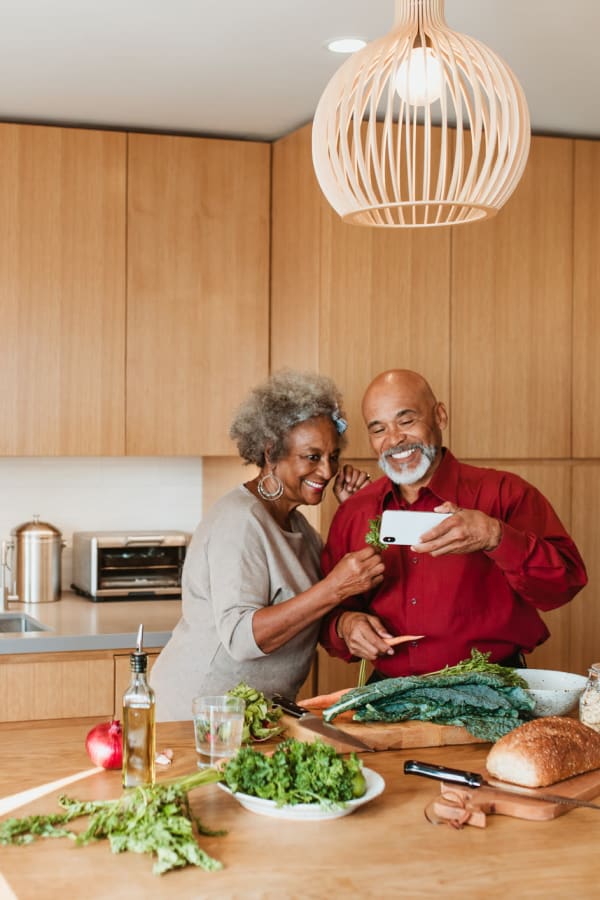 Two residents cooking something delicious in their modern kitchen at West Park Senior Living in San Dimas, California