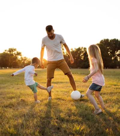 Resident man playing with kids in the park near The Edison at Madison in Madison, Alabama