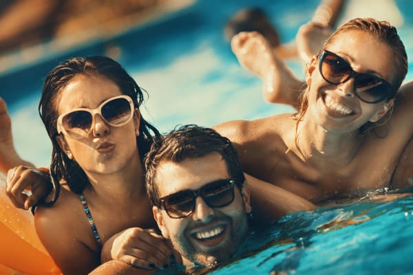 Friends swimming in the pool at Woodcreek Apartments in Huntsville, Texas
