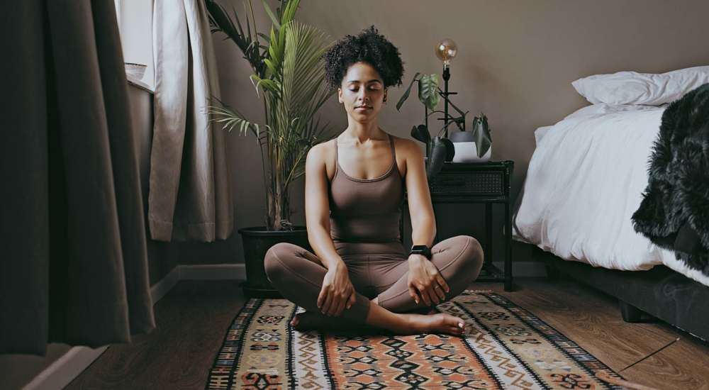 Resident woman doing yoga in her bedroom at Hawks Prairie Apartments in Lacey, Washington