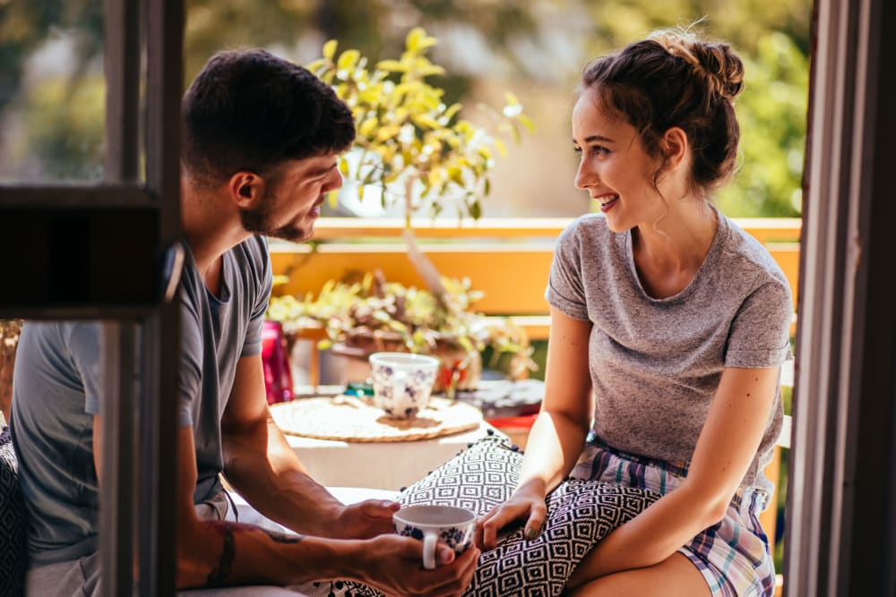 Couple enjoying coffee and conversation on the private balcony outside their apartment at 23Hundred @ Ridgeview in Plano, Texas