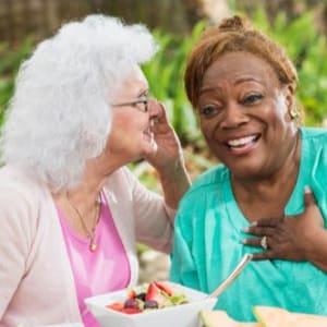 Resident whispering to a staff member at a Arcadia Communities community