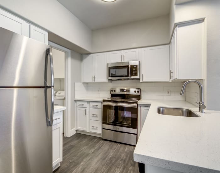 Modern kitchen with granite countertops and subway tile backsplash in model home at Lumiere Chandler in Chandler, Arizona