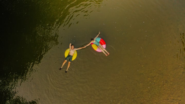 Overhead shot of couple on innertubes floating down river