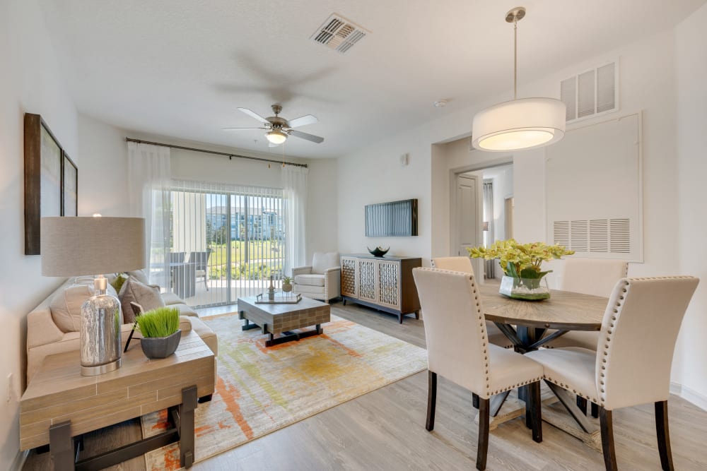 Open floor plan living room with dining area and balcony at Champions Vue Apartments in Davenport, Florida